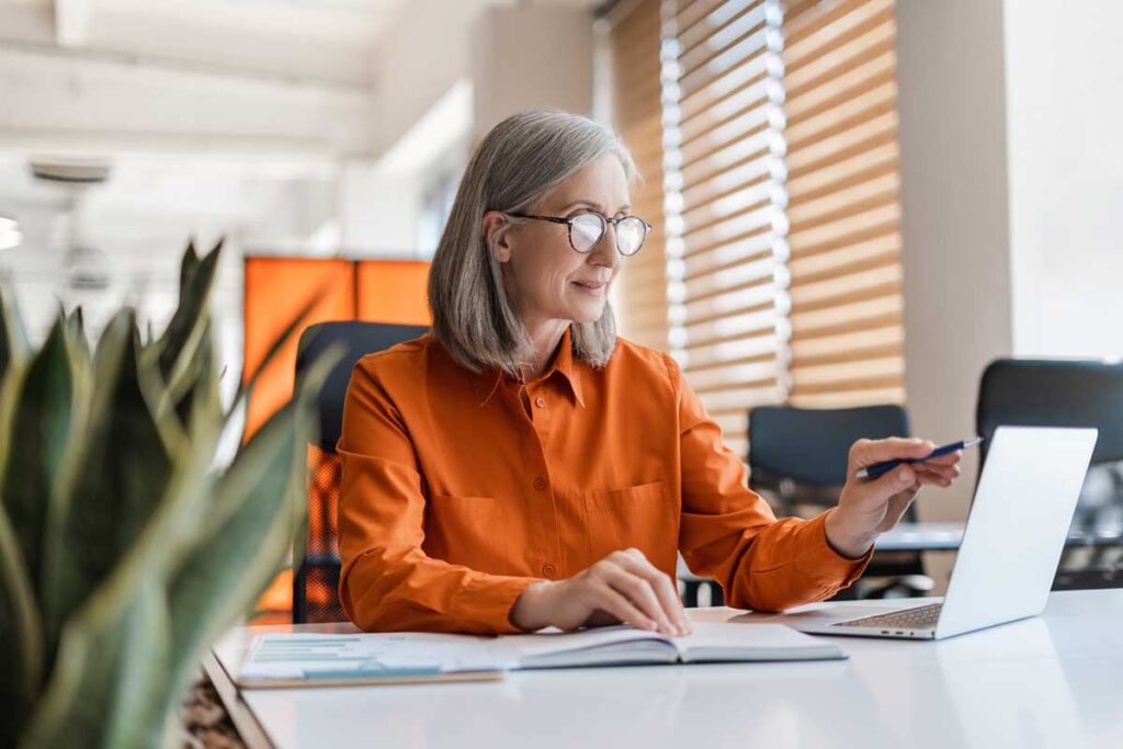 Businesswoman reviewing charts and making notes beside a laptop